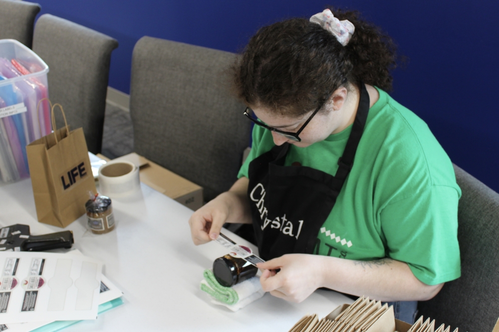 Texas Sweet Heat Jam employee Chrystal Urias labels a jar of jam. (Daniel Schwalm/Community Impact)